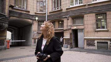 mooi vrouw wandelingen in de omgeving van stad en duurt foto's van oud architectuur. actie. vrouw fotograaf duurt afbeeldingen van oud stad architectuur. vrouw wandelingen door terug straten van stad video