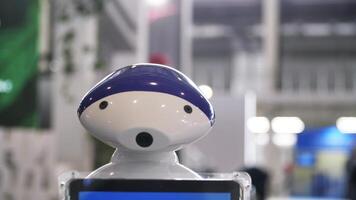 futuristisch Roboter beim das Ausstellung von modern Technologien. Medien. schließen oben von süß Blau und Weiß Roboter ziehen um es ist Kopf mit Eingerichtet Kamera, Zukunft und Technologie Konzept. video