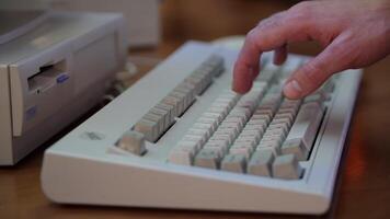 Close-up of man typing on retro keyboard. Media. Man uses old computer, typing on old keyboard. Old computer equipment in working order video