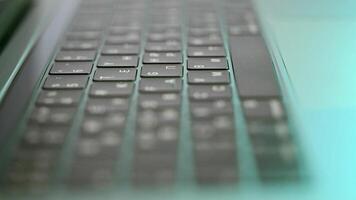 Side view of laptop or computer details, black keyboard with white symbols. Action. Extreme close up of backlit keyboard with flowing camera focus. video