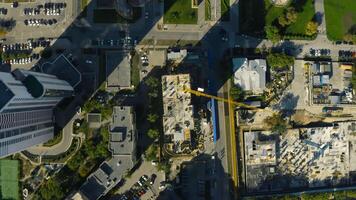 Vertical top view of construction crane in city. Stock footage. Building under construction in center of modern city on sunny summer day. Construction crane in city center video