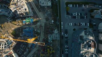 Vertical top view of construction of circular building. Stock footage. Construction site of building near parking lot in city center. Construction of stadium in center of residential city on sunny video