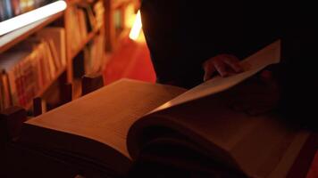 Man reading large mysterious book. Stock footage. Close-up of mysterious man reading ancient forbidden book in library. Secret society with books in night library video