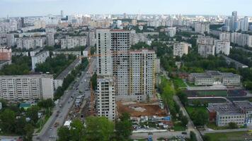 Top view of construction of multi-storey building in city. Stock footage. Construction of multi-storey building in city center on summer day. Panorama of modern city with construction of high-rise video