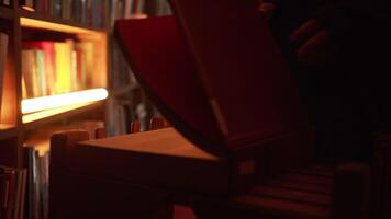 Close-up of mysterious man opening large book. Stock footage. Man opens book in dark library with flashing light. Secret society with mysterious books in night library video