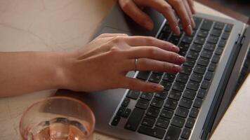 avvicinamento di bellissimo donna digitando su il computer portatile. azione filmato. bellissimo femmina mani siamo digitando su il computer portatile tastiera del computer. femmina libero professionista lavori a il computer portatile nel bar video