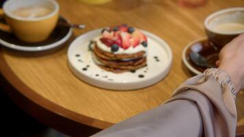 Close-up of beautiful woman having lunch in cafe with coffee and dessert. Stock footage. Woman drinks coffee with beautiful dessert in cafe. Beautiful aesthetic lunch with dessert and coffee in cafe video