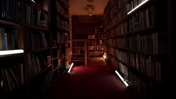 nacht bibliotheek met knippert lichten. voorraad filmmateriaal. gang met boekenkasten in nacht bibliotheek. knippert lichten in gangpad tussen boekenkasten van nacht bibliotheek video