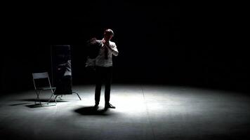 uomo nel completo da uomo solo su Teatro palcoscenico. azione filmato. singolo attraente uomo nel completo da uomo è giocando su palcoscenico di Teatro. uomo nel completo da uomo con specchio è solo su buio teatrale palcoscenico video