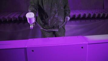 Expert is using a spraying gun to paint metal pieces at a painting factory facility. Clip. Professional hand spray painting of a metal part in purple color. video