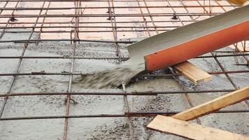 Pouring concrete mixture to the reinforcing mesh and a house foundation. Clip. Pouring liquid cement at a construction site. video