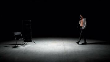 Man in suit alone on theater stage. Stock footage. Single attractive man in suit is playing on stage of theater. Man in suit with mirror is alone on dark theatrical stage video