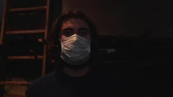 Portrait of a young man wearing protective medical mask in front of wooden ladder and the screen with movie. Media. Concept of prevention Covid 19 pandemic and wearing masks at work. video