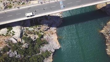 Antenne oben Aussicht von ein Brücke Kreuzung das Blau Meer und Felsen. Clip. Sommer- Marine Landschaft mit Türkis Wasser und Beton modern Brücke mit Touristen. video