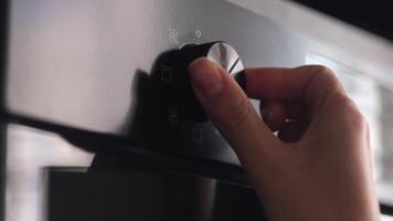 Close up of woman hand turning round temperature oven handle in the kitchen at home. Concept. Kitchen utensils for easy cooking. video