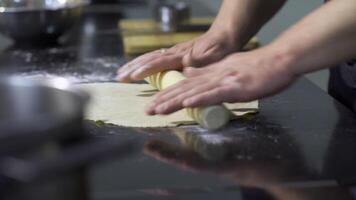 Close-up of cook thinly rolling out dough with rolling pin. Art. Professional chef rolls out dough for thin dish. Rolling out dough for dumplings video