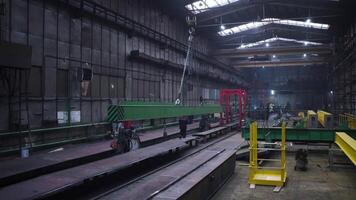 Metal beam is moved on chains in factory. Clip. Steel beam suspended on chains is dragged at factory. Suspended beam on chains moves around factory video