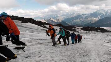 Viajantes subir ao longo a montanha passar em a gelo declive. grampo. conceito do extremo esporte e hobbies, alpinistas em a fundo do montanha alcance e pesado nuvens. video