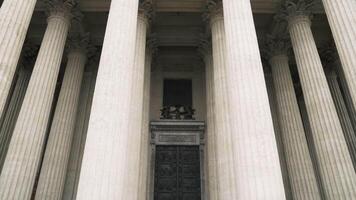 Big carved columns made of white marble and giant black iron door. Action. Details of a cathedral or a temple with colonnade, concept of ancient architecture. video