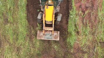 Haut vue de excavatrice travail dans champ. agrafe. bulldozer efface terrain de terre avec vert fourrés. bulldozer efface une champ de vert herbe video