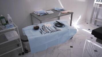 A table with surgical sterile instruments, scalpels and clamps. Action. Details of the operating room, prepared clean medical instruments, devices for a surgery and a bowl with iodine. video