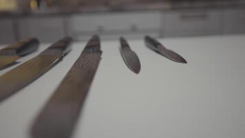 Close up of knives set lying on a white table surface in the kitchen. Action. New sharp steel knives, concept of cooking. video