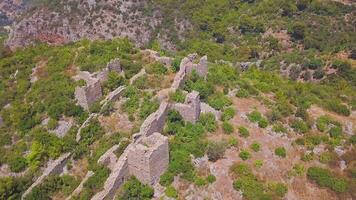 Top view of ancient ruins of castle on hill. Clip. Beautiful ruins of castle on green hill towering over old village. Historical ruins of ancient castle in wooded mountains video