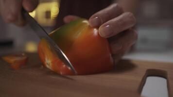 proche en haut de femme mains en utilisant cuisine couteau à tranche et Couper le cloche poivre sur une en bois planche. action. concept de en bonne santé légume régime et cuisine aliments. video