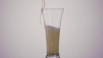 A hand of a drunk man pouring beer inside a long transparent glass and spilling it on the table. Action. Close up of beer alcoholic drink with a lot of foam on white background. video