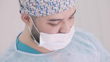 Male doctor in sterile clothing and mask during surgery. Action. Concept of medicine, medical doctor performing procedure at a hospital. video