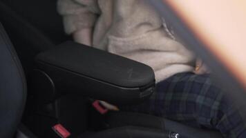 Woman putting her phone inside the armrest inside a passenger car and closing it. Action. Concept of transportation, interior of a modern vehicle. video