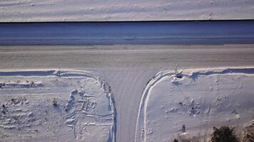 T-förmig Kreuzung auf ein Winter sonnig Tag. Aktion. Antenne oben Aussicht von ein Landschaft Straße Segment bedeckt durch Schnee. video