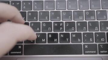 The man is texting quickly with his hands on a black keyboard with an English-Russian layout. Action. A man writes a letter or a message on on keyboard of a computer or laptop. video