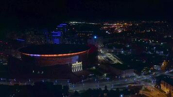 Stadium Arena Yekaterinburg with beautiful illumination all over round shaped facade. Stock footage. Aerial view of night shining buildings, concept of sport and architecture. video