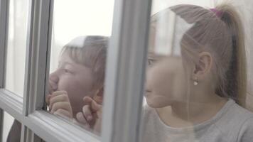 Little children boy and girl standing behind the door with glass inserts. Action. Sister and brother standing excited together behind the doorLittle children boy and girl standing behind the door with video