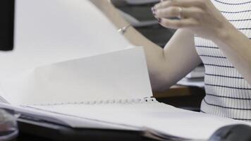 Female office worker doing paperwork at a desk with a computer, close up view. Action. Woman reading data report, examining documents. video