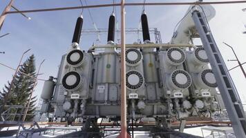 High voltage electrical substation on blue cloudy sky background. Action. Bottom view of a transformer near street lamps, concept of energy system. video