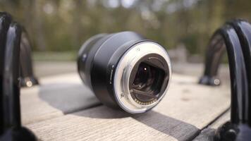 Close up of camera lens lying on rotating children roundabout on green blurred trees background. Action. New camera lens is forgotten on children playground. video