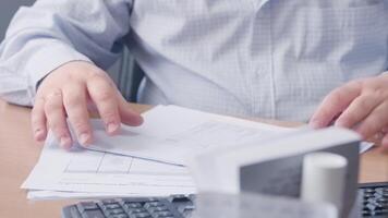 Close-up of office worker checking papers at workplace. Action. Accountant or manager checks documents sitting at desk. Businessman checks documents before signing them video