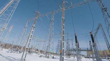 Poles and cables of power plant in winter. Action. Power plant in field on sunny winter day. Beautiful power plant with lots of poles and cable conductors video