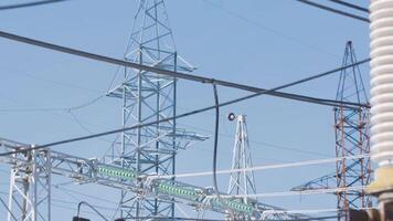 Power poles on background of blue sky. Action. Beautiful electric poles on blue sky background. Electrical substation with poles and cables. Power generation and transmission industry video