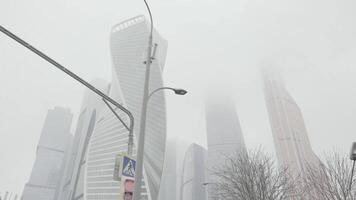 Bottom view of a street lamp and traffic lights with a breathtaking modern architectural ensemble on the background. Action. Moscow city towers on a foggy day. video