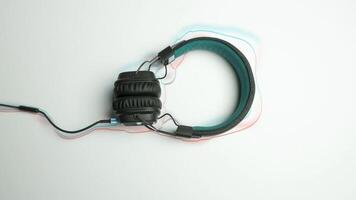 Headphones on white background with animated lines. Animation. Headphones frame moving colored lines on white background. Real headphones on background of repeating shape of animated lines video