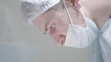 Close-up of masked surgeon during surgery. Action. Young professional surgeon in mask looks down. Surgeon is concentrating on performing operation. Beautiful surgeon on internship video