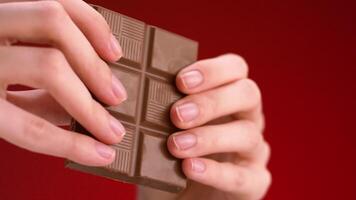 Man breaking chocolate. Stock footage. Close-up of hands breaking chocolate bar into two parts. Delicious chocolate is broken into pieces on isolated background video