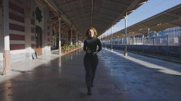 Beautiful woman with camera walks on sunny day. Action. Attractive female photographer confidently walks on background of old building. Female photographer looks like model video