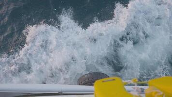 View from side deck of ship on waves. Action. Ship moves through waves of blue sea. Waves beat against moving ship of ship video