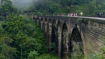 antigo pedra aqueduto dentro verde montanhas. Ação. antigo pedra ponte com arcos dentro verde montanhas. turistas andar em antigo ponte dentro vale do tropical montanha florestas video