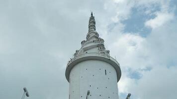 sri lanka, kandy - juli 29, 2023. ambuluwawa torn sri lanka. handling. se från Nedan av vit spiral torn på bakgrund himmel. skön höga torn med vriden steg på Fasad video