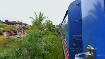 View from window of moving train in jungle. Action. Traveling train in midst of green forest in tropical mountains. Beautiful train ride in tropics on cloudy day video